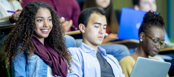 Close-up of three students sitting in university lecture hall and observing lecture